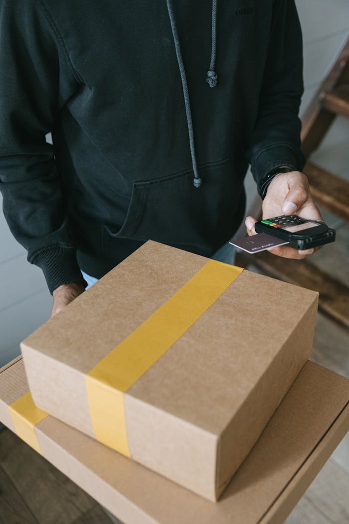 Close-up of courier using card reader for cashless transaction during package delivery.
